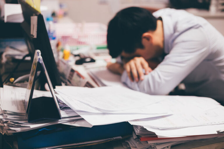 Stressful and frustrated young Asian business office worker having overwork problem crisis with tons of paperwork load